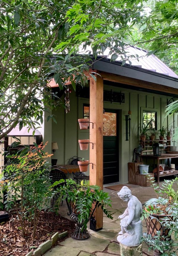 Lush garden with small porch, potted plants, and a classical stone statue