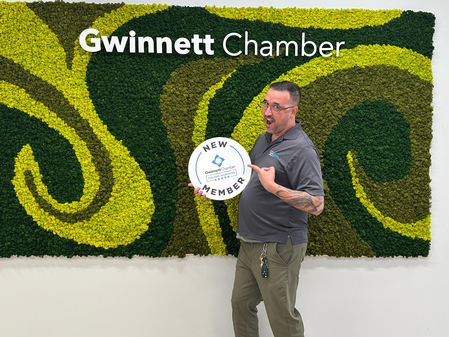 Man holding new member sign in front of green wall with Gwinnett Chamber logo