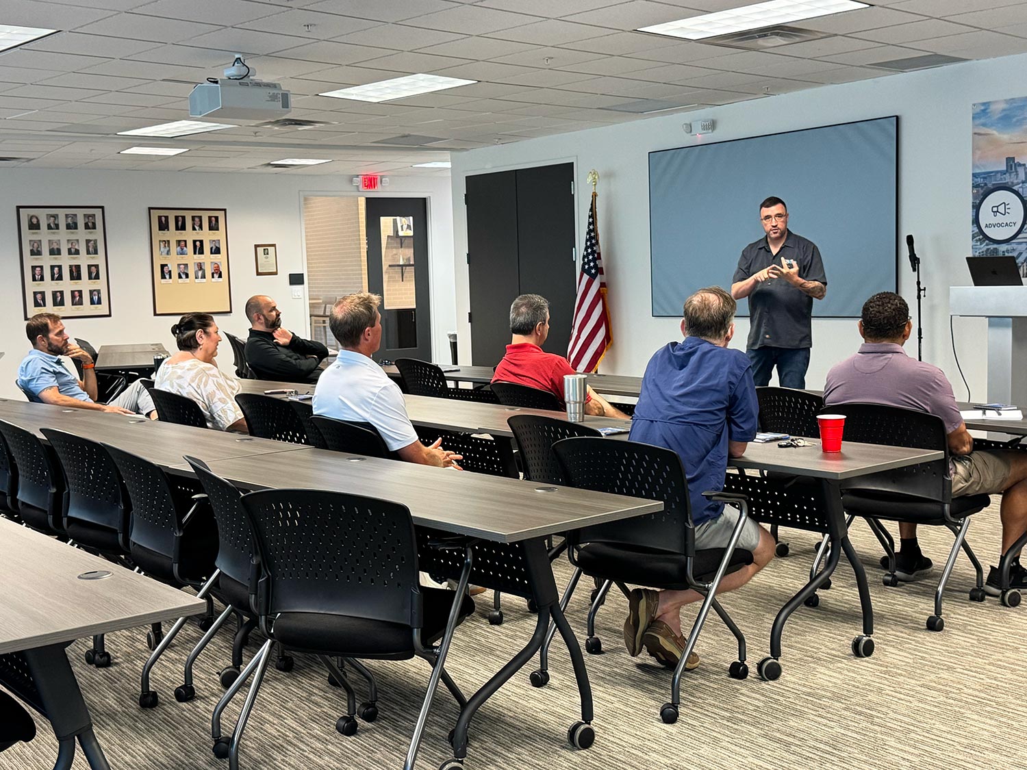 Instructor speaking to audience in a training session with U.S. flag visible