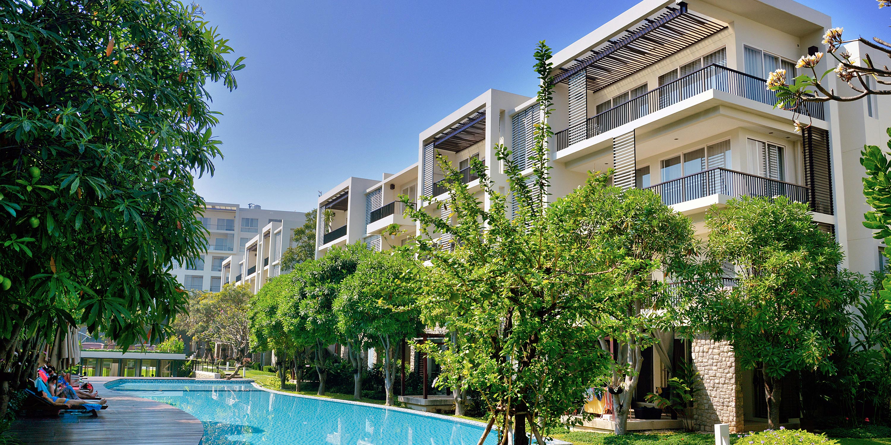 Exterior view of a modern MDU with a swimming pool and lush greenery.