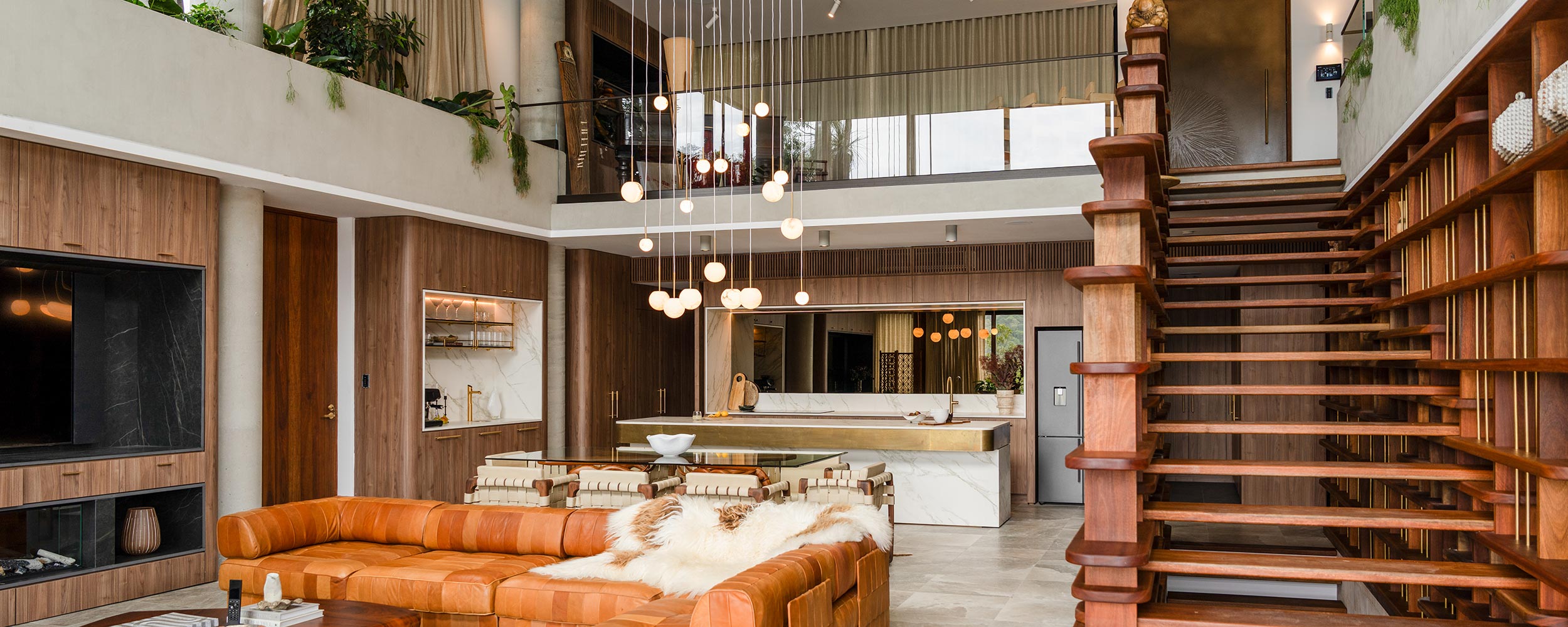 Stylish open-plan living space with wood accents, modern staircase, and pendant lighting