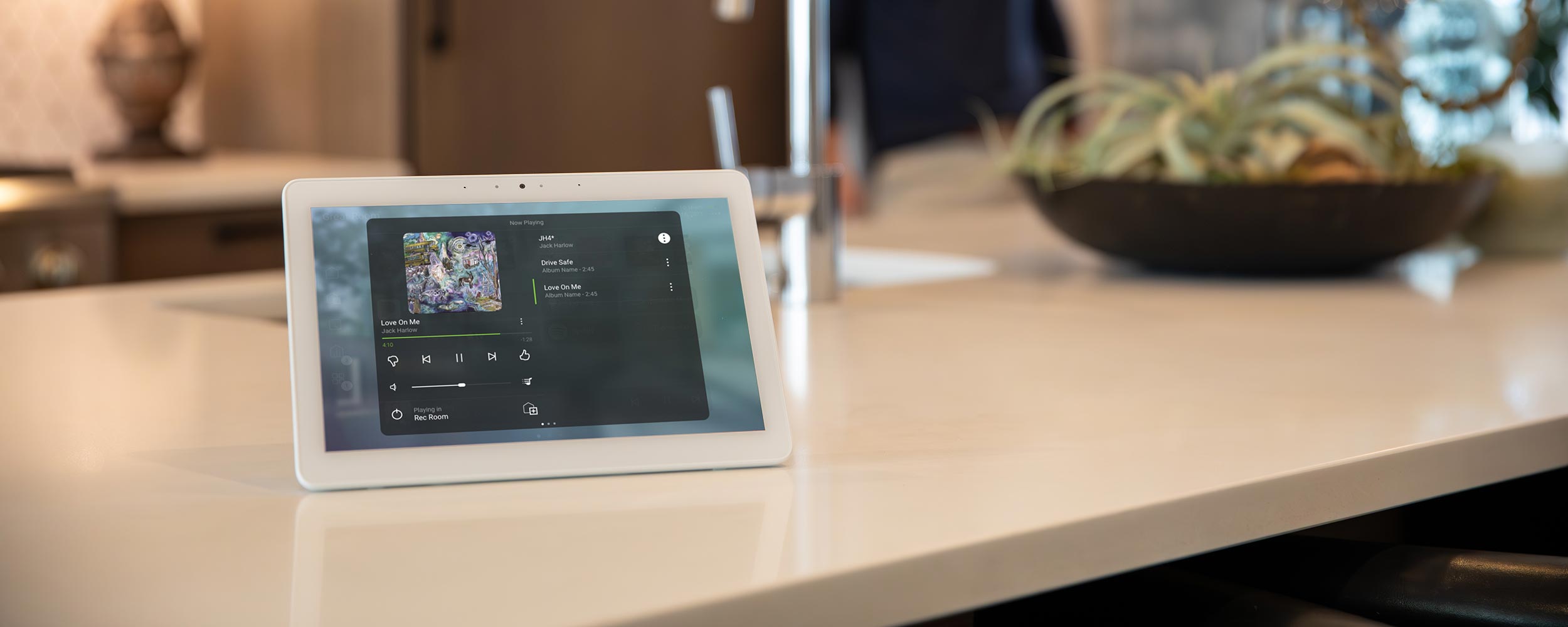 Smart tablet on kitchen counter displaying music controls
