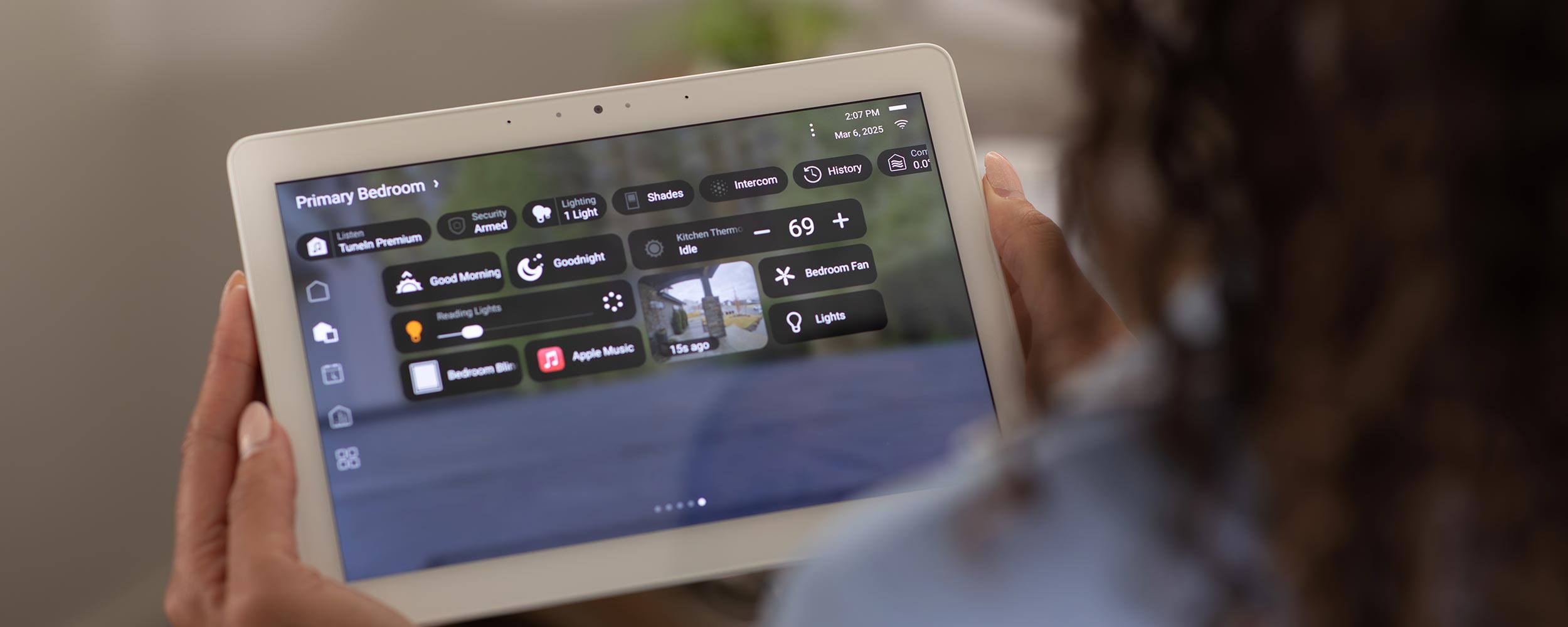 Close-up of hands holding a smart tablet showing full home automation system