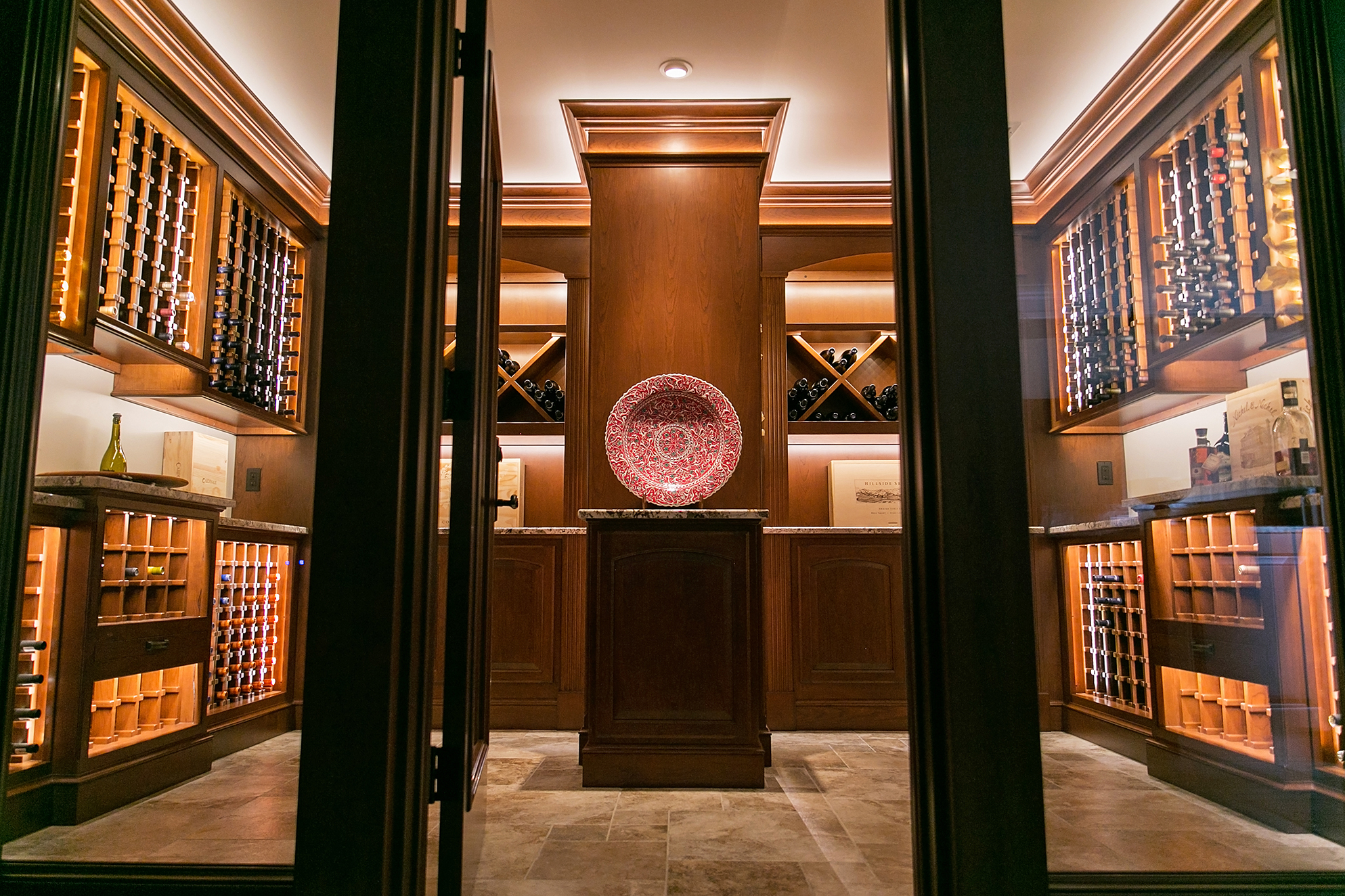 A wine cellar featuring illuminated wooden racks and a decorative centerpiece.