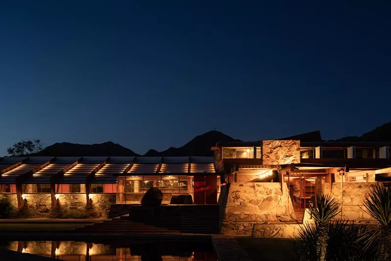 Luxury hillside home at dusk with warm architectural lighting inside and out