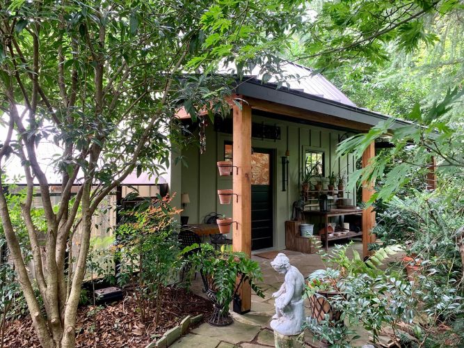 Alternate angle of porch surrounded by trees and plants, statue in front