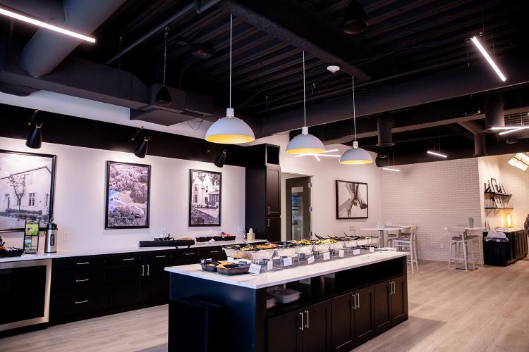 Modern kitchen setup with food trays on island and black-and-white framed artwork