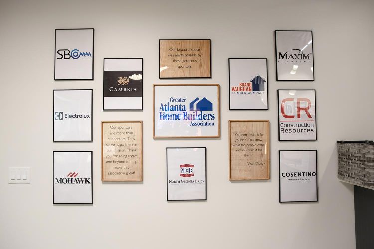 Framed sponsor logos and quotes on a white wall in a modern office setting