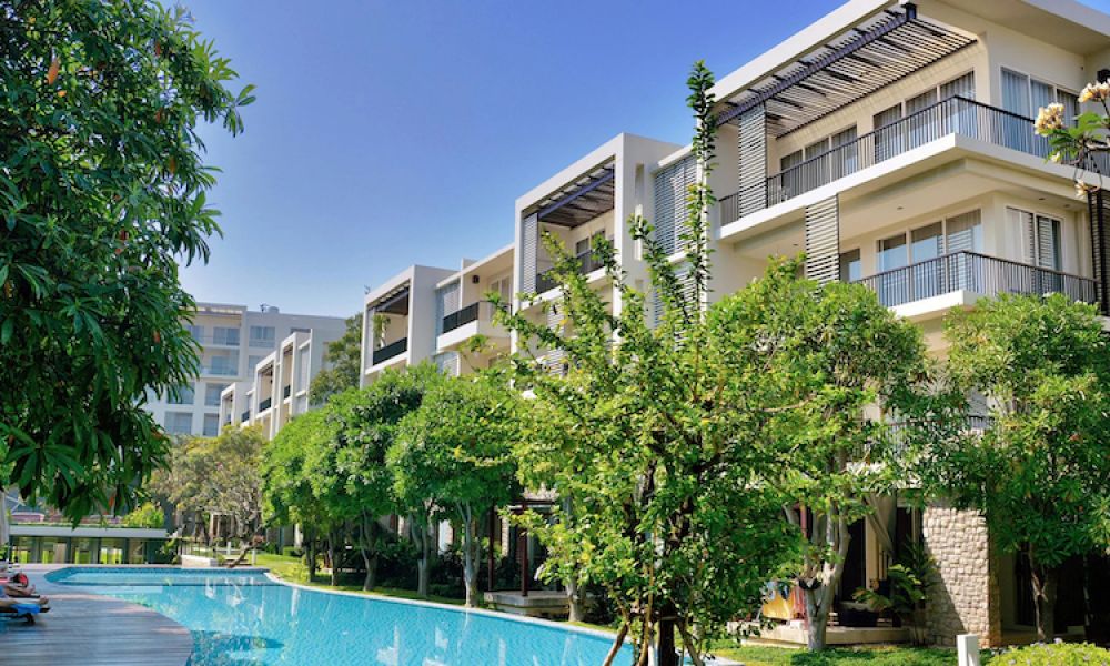 The outside of a modern apartment building, looking at the pool area.