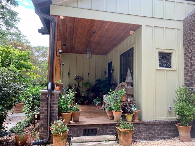 Repeated image of watering can beside pots and blooming red geraniums
