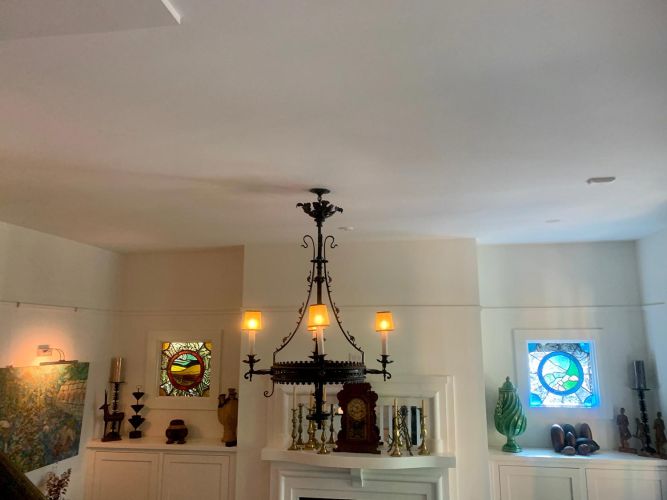 Fireplace mantle flanked by stained glass windows and decorative objects