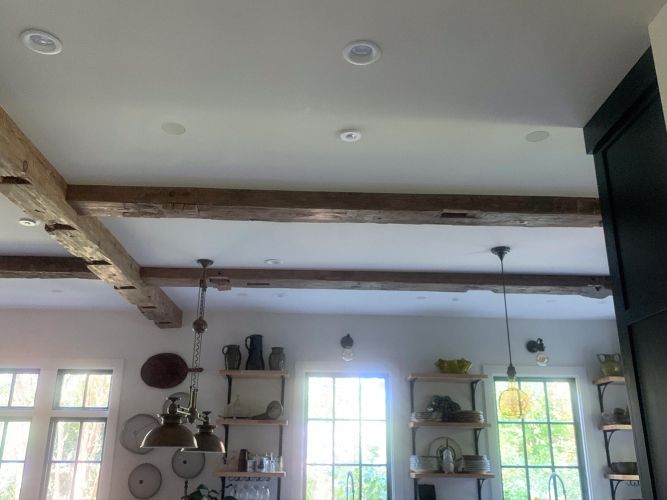 Rustic ceiling with exposed beams over kitchen shelving and window light