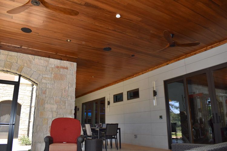 Patio area with red lounge chairs, modern light fixtures, and stone-accented walls