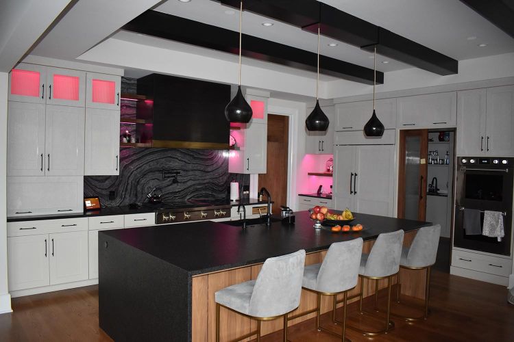 Modern kitchen with black island, light gray chairs, and pink accent lighting