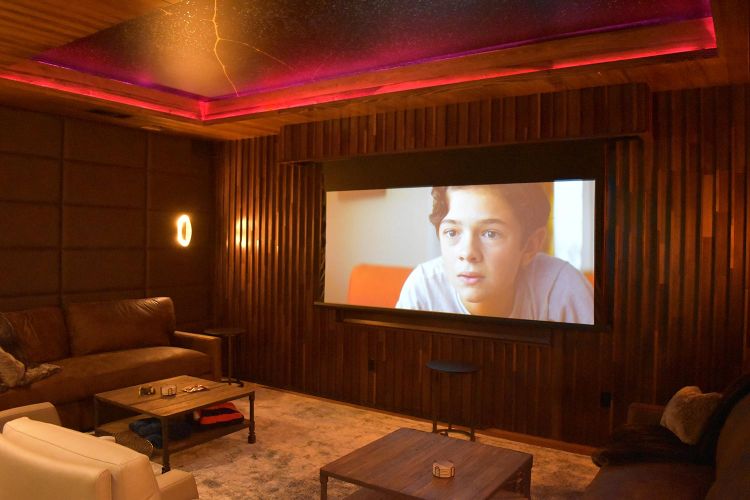 Home theater room with large screen, wood panel walls, and glowing ceiling