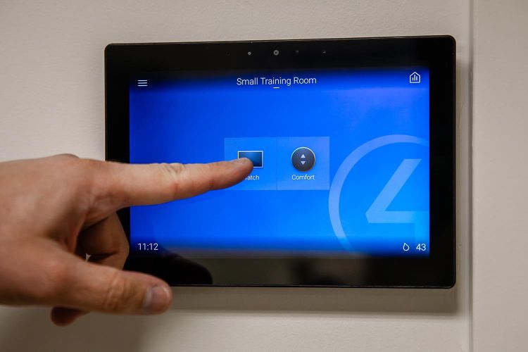 Finger selecting ‘Watch’ option on wall-mounted control panel