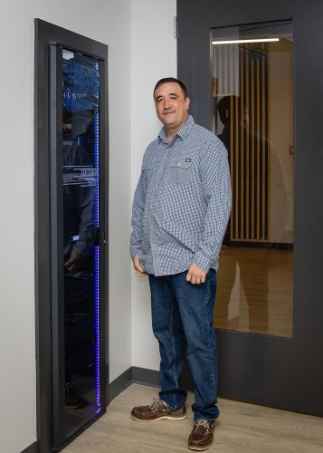 Technician standing beside an AV rack with purple LED lighting