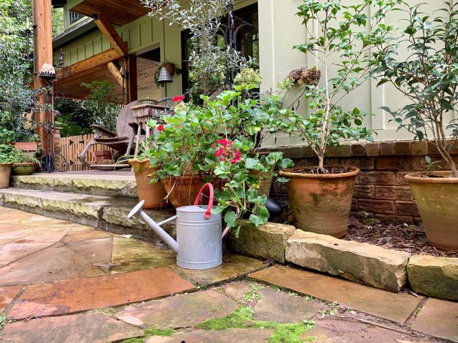 Porch steps with rocking chair and flower pots leading to garden pathway