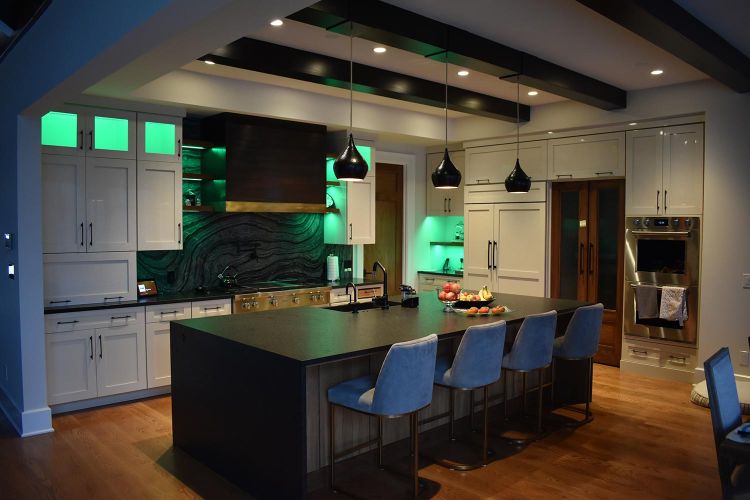 Elegant kitchen with green lighting and blue upholstered chairs