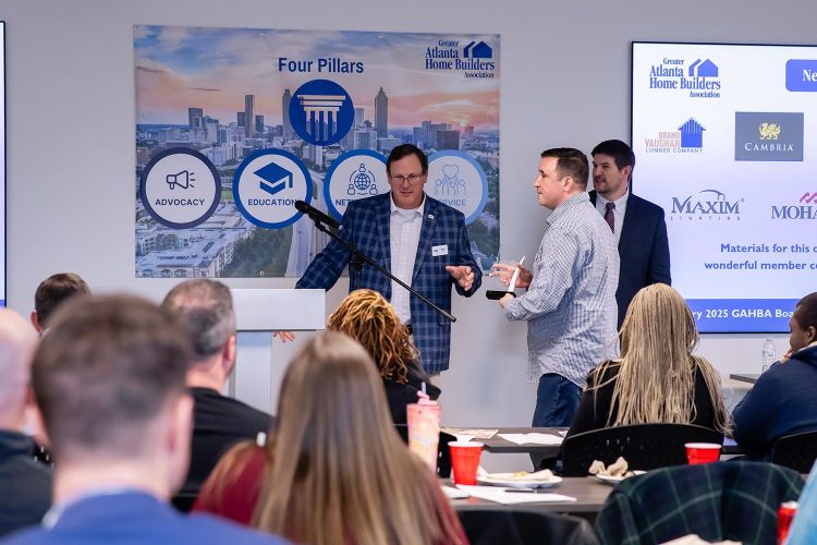 Speaker addressing audience while award recipient holds a trophy