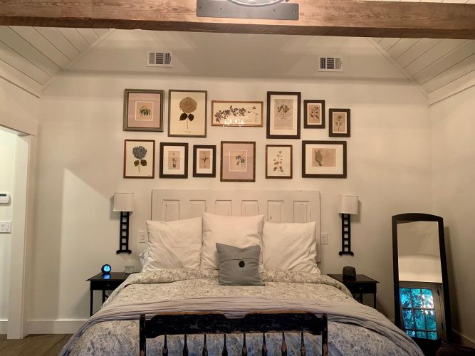 Cozy bedroom with botanical wall art, wood beam ceiling, and decorative pillows