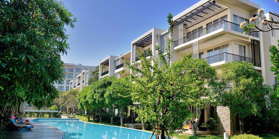 The outside of a modern apartment building, looking at the pool area.