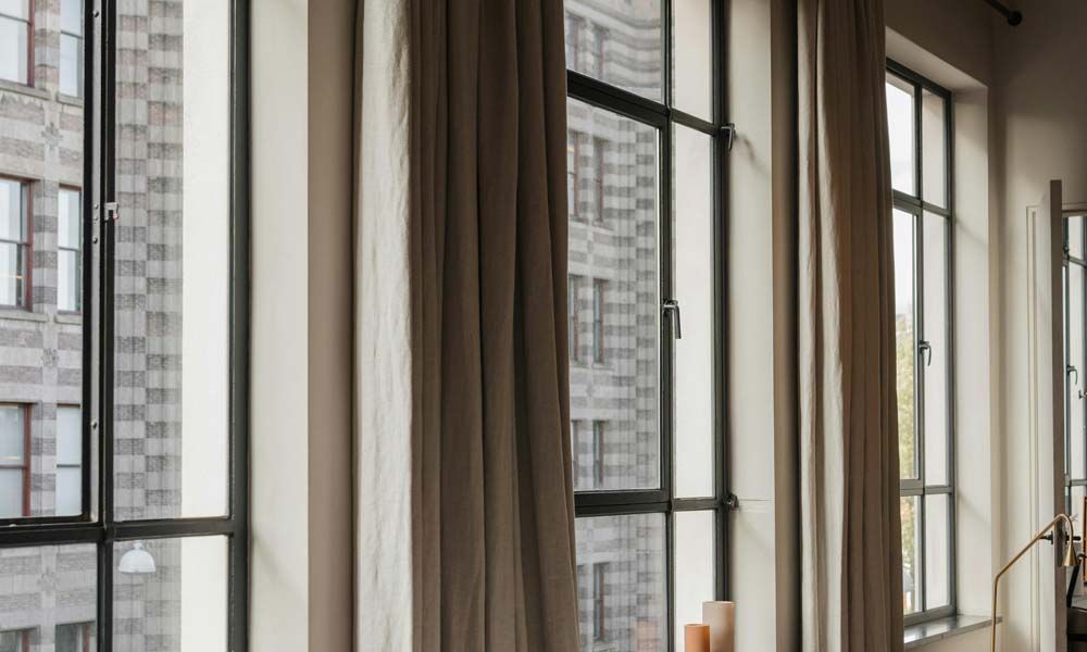 Tall loft windows with brown curtains in urban apartment