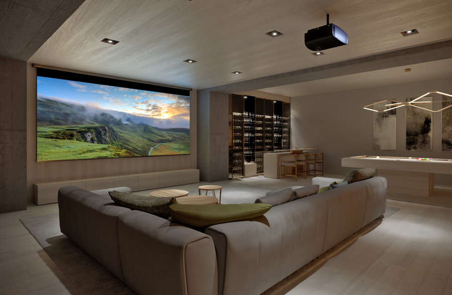SBCOMM_MayImpactContent1_Whole Home Audio_PHOTO A media room with a sectional, pool table, and wine bar. A Sony projector displays a landscape image on a large screen.
